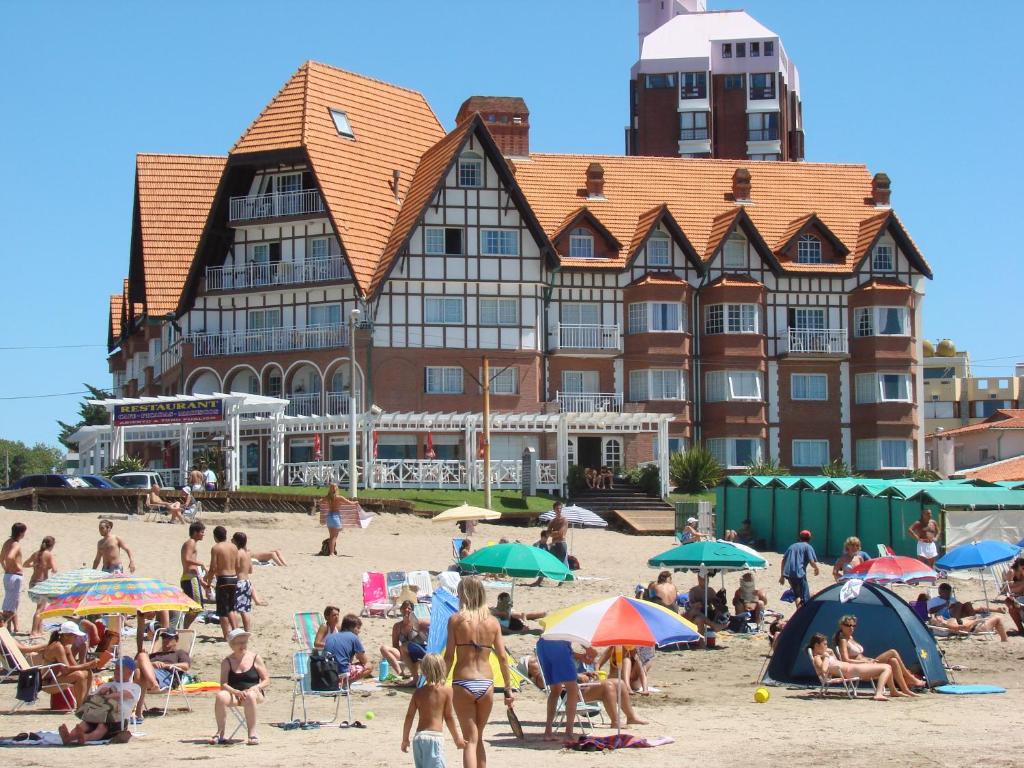 um grupo de pessoas numa praia em frente a um edifício em Gemelos Apart em Villa Gesell