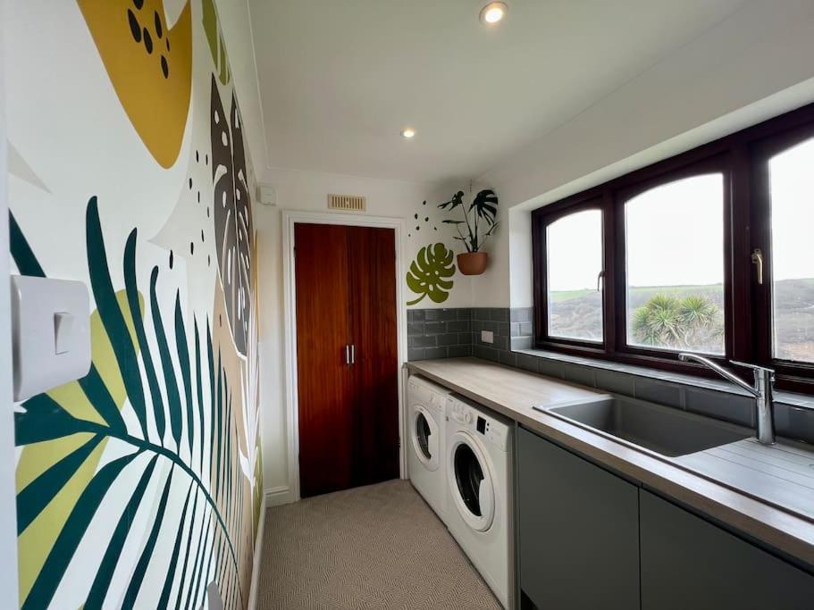 a kitchen with a sink and a washing machine at Valley Lodge House - Porth Newquay in Newquay