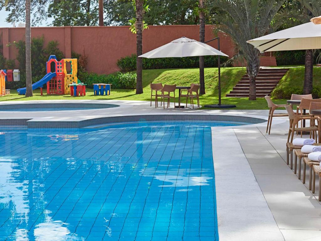 a swimming pool with chairs and a playground at Novotel Campo Grande in Campo Grande