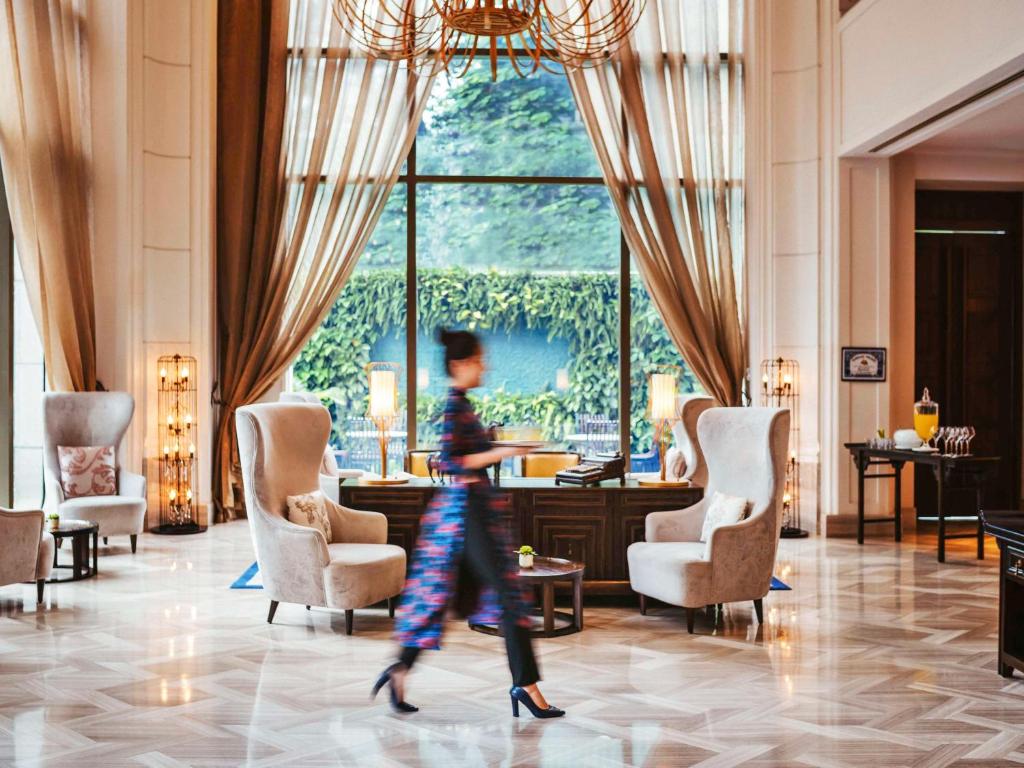 a woman walking through the lobby of a hotel at Hotel Des Arts Saigon Mgallery Collection in Ho Chi Minh City