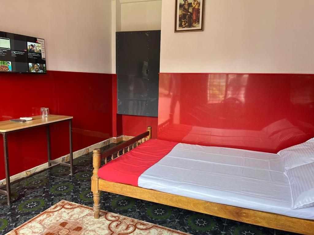 a bedroom with a bed with a red wall at KRK ROOMS Kottarakara in Kottārakara