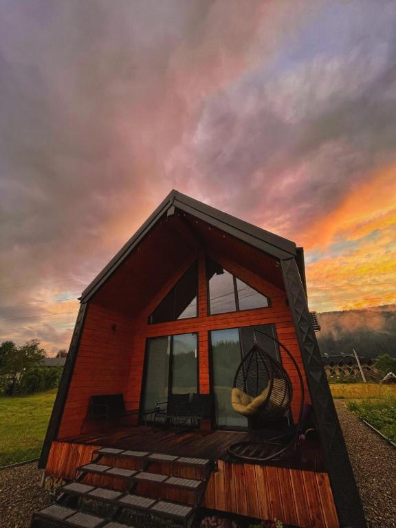a small house with a large window and a sunset at Barn S&S House in Mykulychyn