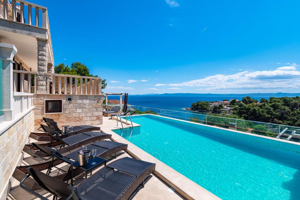 a villa with a swimming pool and lounge chairs at Villa Kadena - Luxury Seaside Villa with Private Heated Pool in Selca