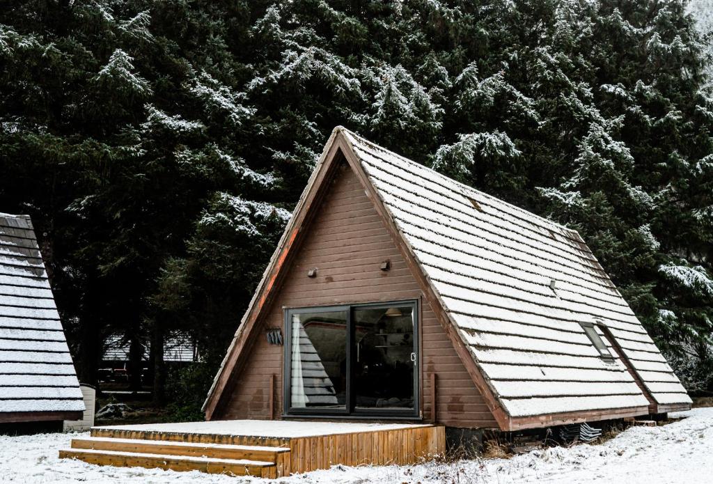 una pequeña casa con techo en la nieve en The Triangle Lodge en Invergarry
