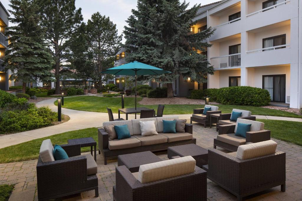 a patio with couches and tables and an umbrella at Courtyard by Marriott Boulder in Boulder