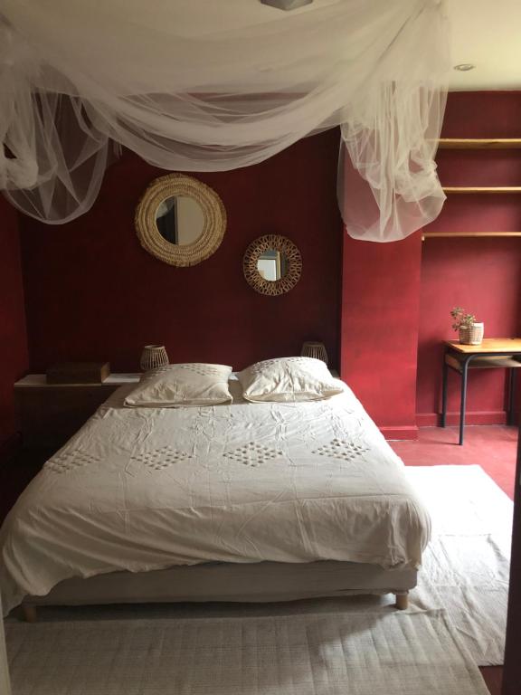 a bedroom with a white bed with a red wall at Bel appartement et jardin chez Maison Devaux in Rion-des-Landes