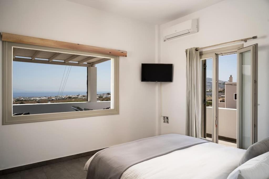a bedroom with a bed and a large window at In the heart of Fira & free pool - Nychteri suite in Fira