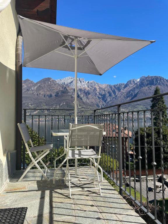 a table and chairs on a balcony with an umbrella at Casa delle Olive 1 in Oliveto Lario