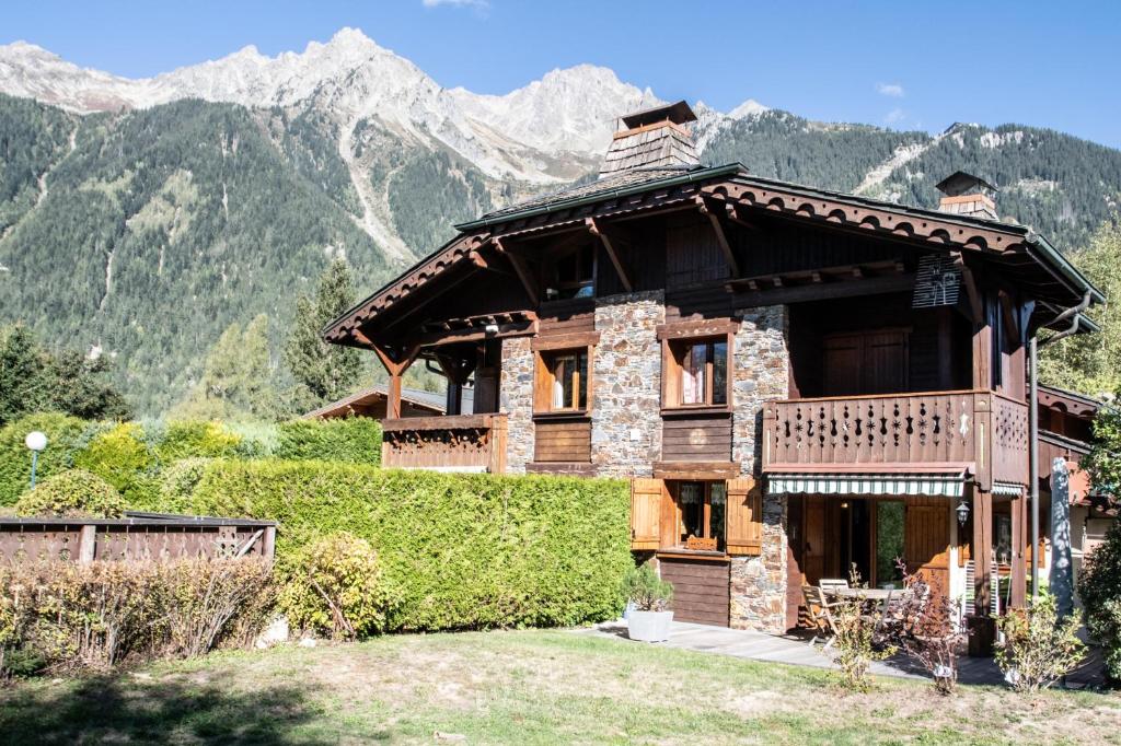 uma grande casa de madeira com montanhas ao fundo em Résidence Chalets Des Bois em Chamonix-Mont-Blanc