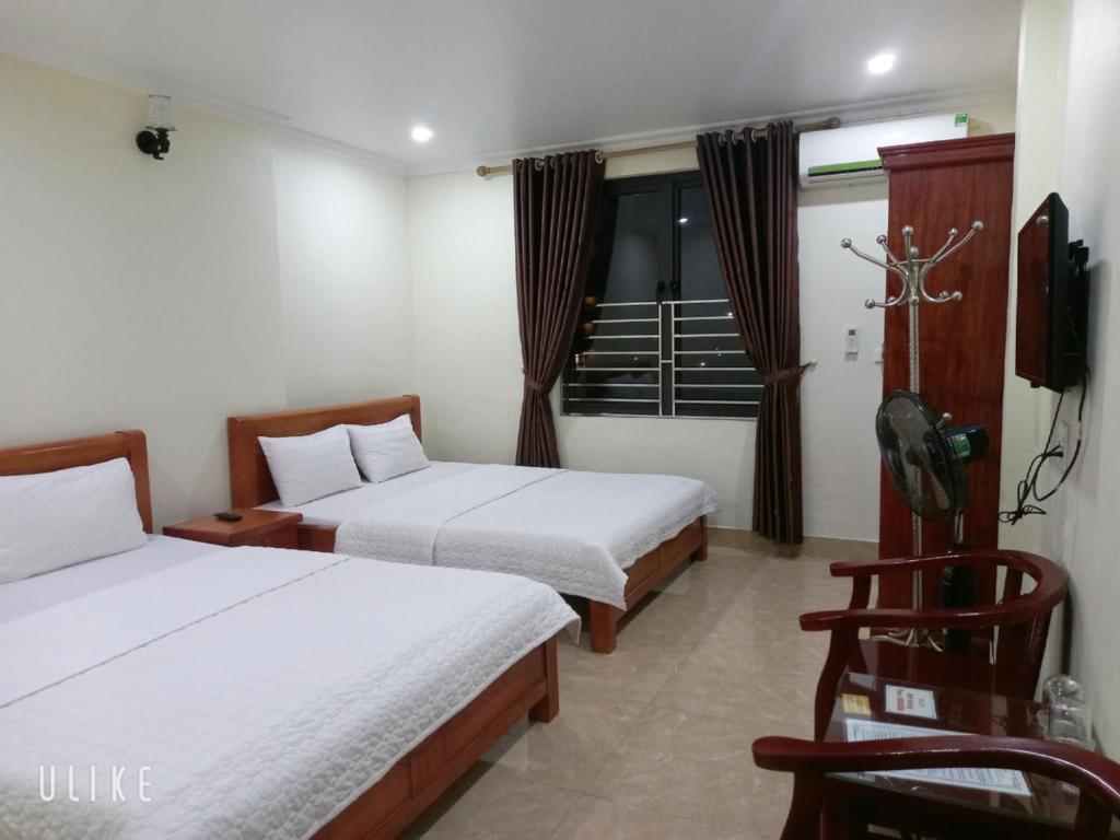 um quarto de hotel com duas camas e uma televisão em Guesthouse Anh Khang em Ha Long