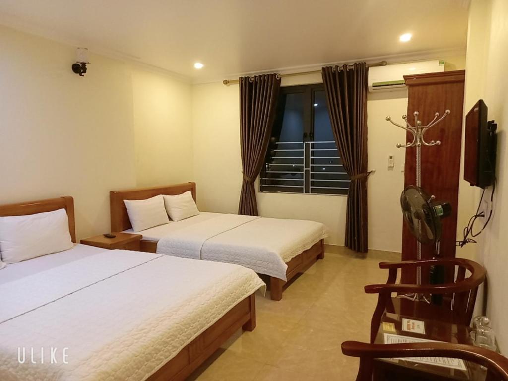 um quarto de hotel com duas camas e uma televisão em Guesthouse Anh Khang em Ha Long