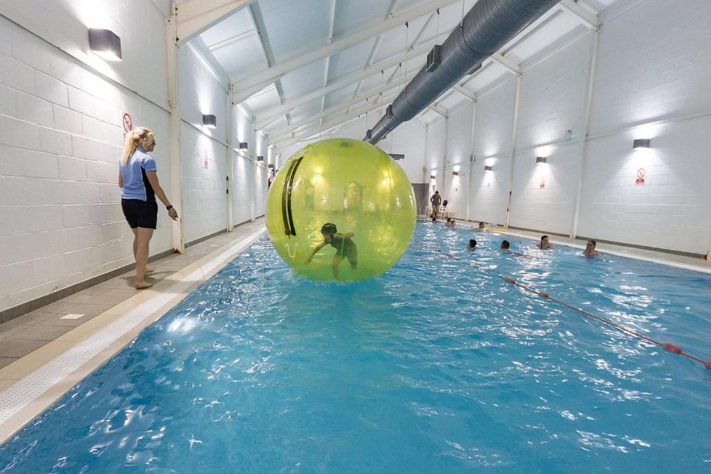 uma mulher numa piscina com uma grande bola verde na água em Filey Bay Beach House Holiday Home The Bay Filey em Filey