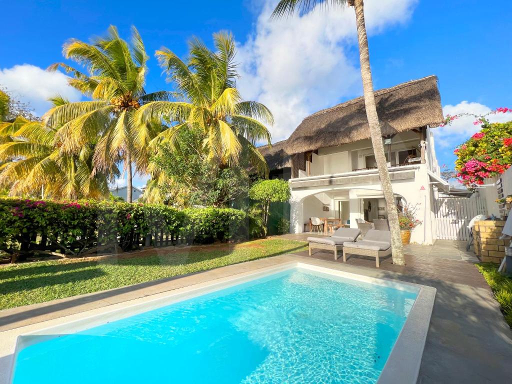 a villa with a swimming pool in front of a house at Caro's Beachfront in Trou aux Biches