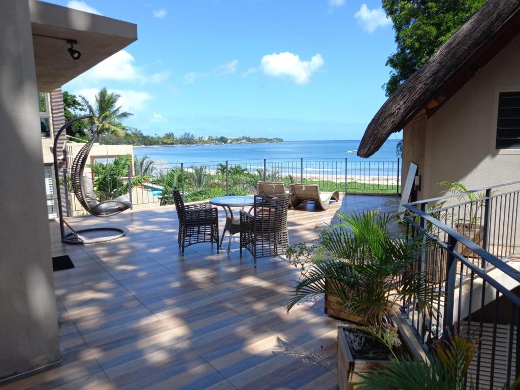 a patio with chairs and a table and the ocean at Beachfront Villa by M&H in Tamarin