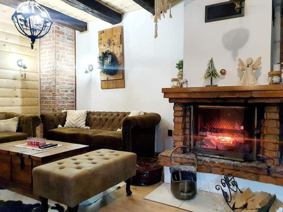 sala de estar con sofá y chimenea en Čarovná chata pri potoku s krbom v interiéri en Lazy pod Makytou