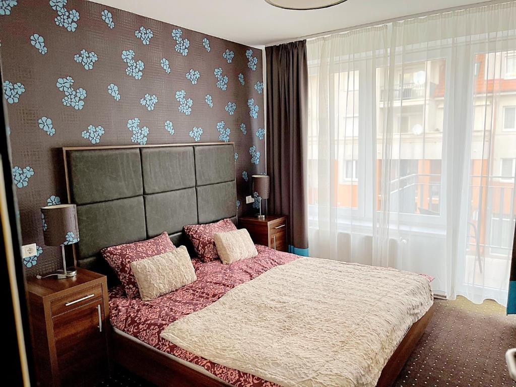 ein Schlafzimmer mit einem großen Bett und einem Fenster in der Unterkunft Plage Brookforest Apartman in Hajdúszoboszló