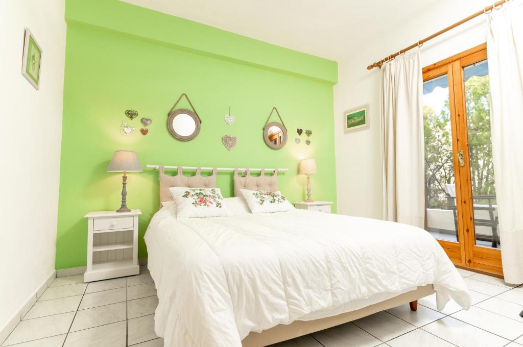 a bedroom with a white bed and a green wall at Xenios Zeus in Skála Nikíta