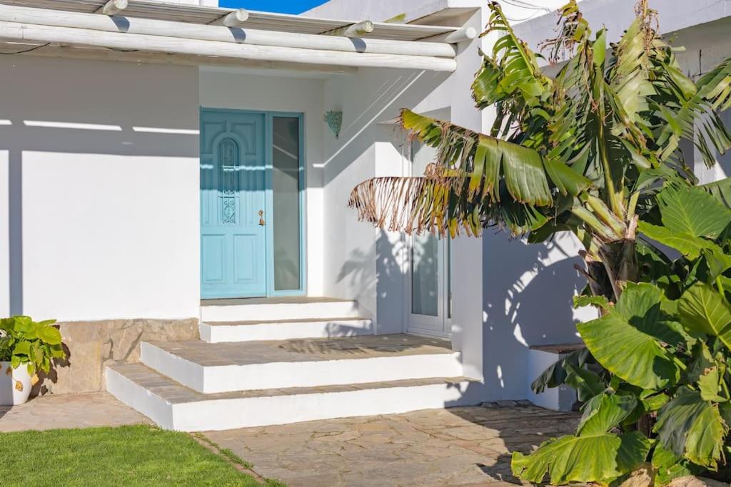 une maison blanche avec une porte bleue et quelques plantes dans l'établissement Casa Rural La Vega 1 en Tarifa, à Tarifa