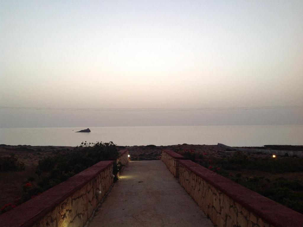 a walkway leading to the ocean at sunset at Archipelagos Apartments in Arkasa