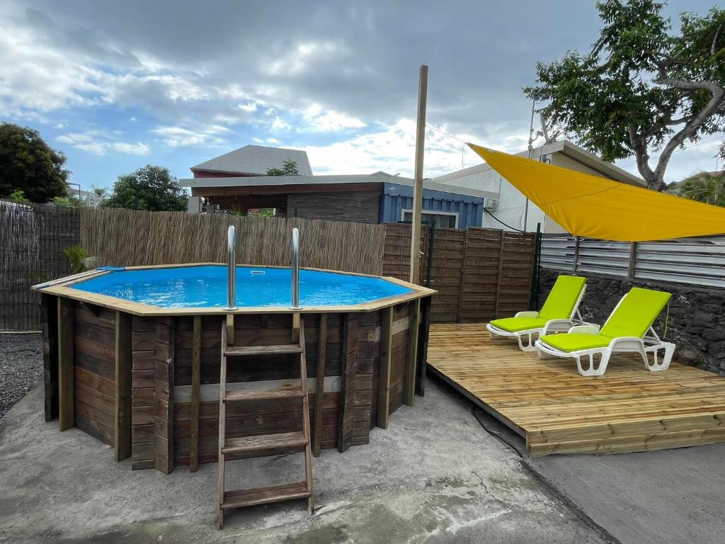 una piscina con 2 sillas y una sombrilla en Ti Caz de Ness, en Saint-Leu