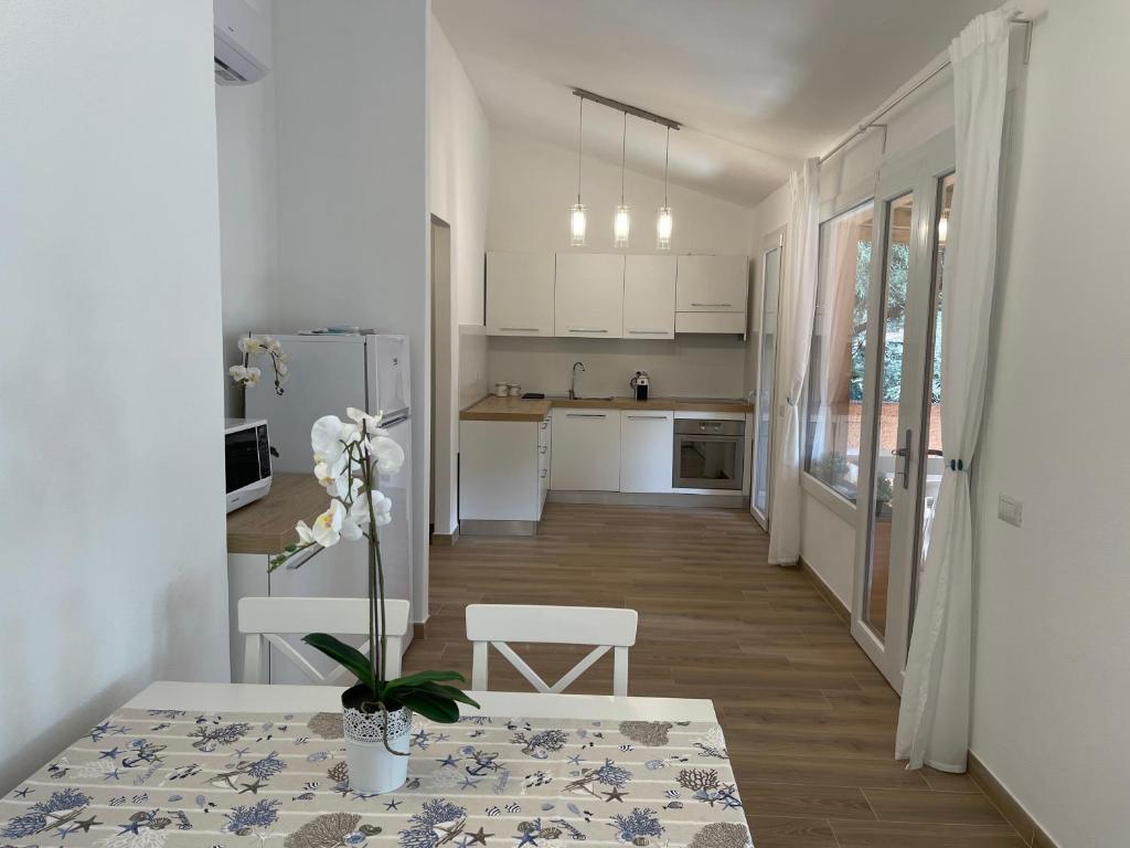 a kitchen with white cabinets and a table with a plant at Beach House Calaverde Village in Santa Margherita di Pula