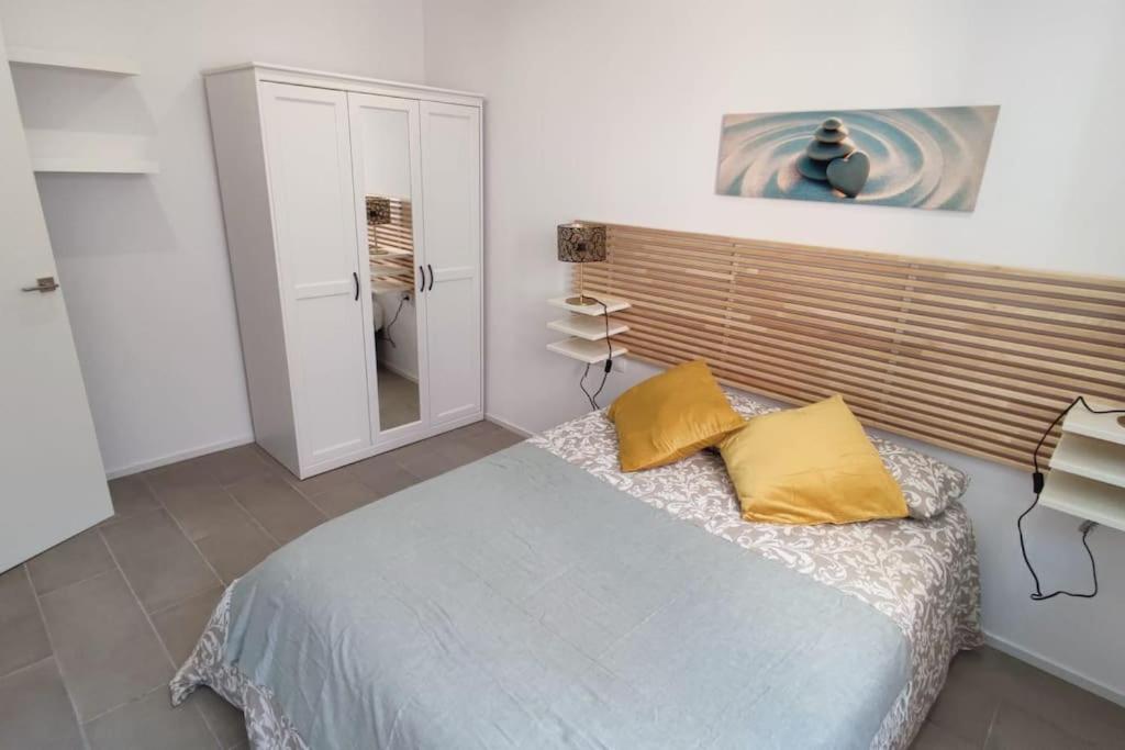 um quarto com uma cama com duas almofadas amarelas em Nuevo apartamento en la playa de Castelldefels! em Castelldefels