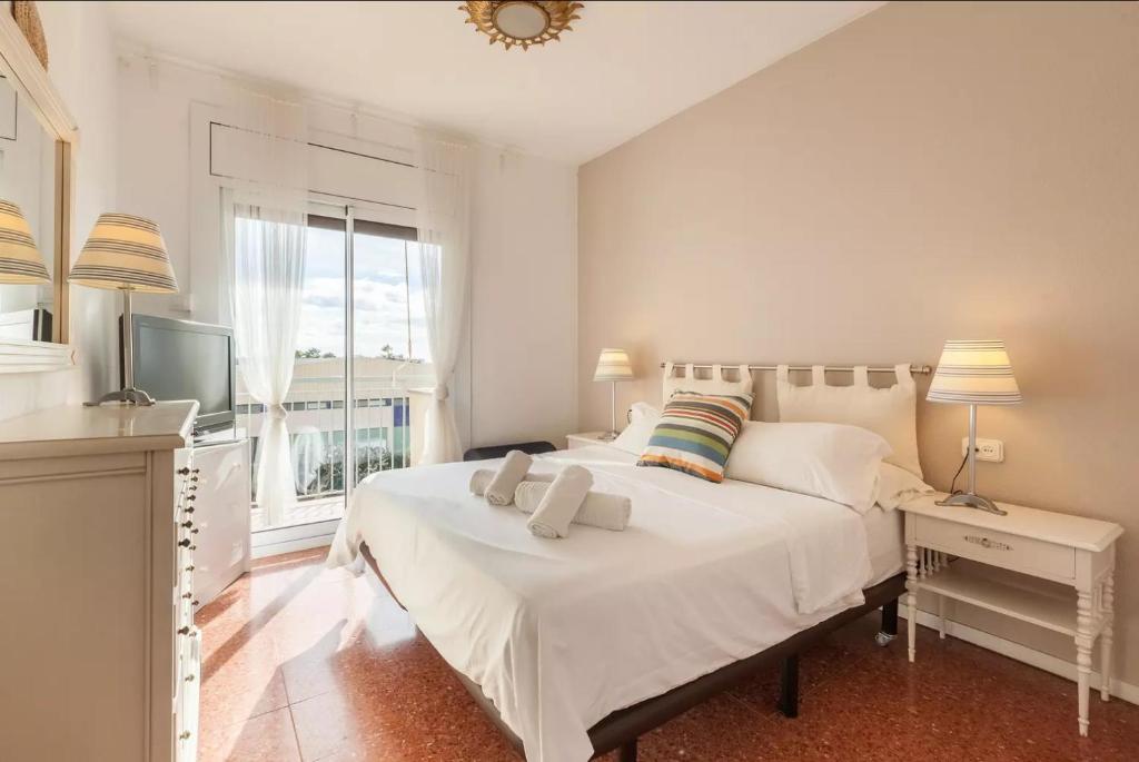 a bedroom with a large white bed and a television at Apartment Muralla in Vilassar de Mar