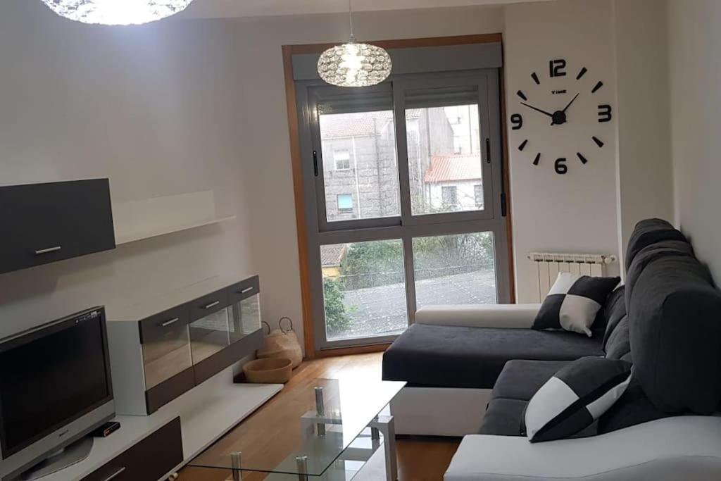 a living room with a couch and a clock on the wall at Maravilloso apartamento en Villagarcia de Arosa in Vilagarcia de Arousa