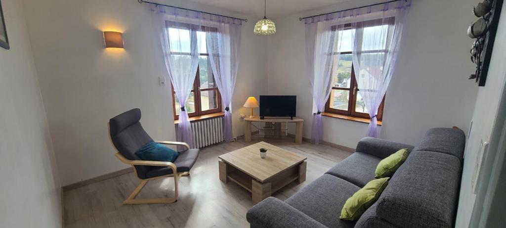 salon z kanapą i krzesłem w obiekcie Appartement accueillant au cœur de La Margeride w mieście Grandrieu