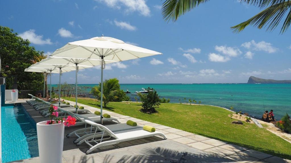 una fila di sedie a sdraio e un ombrellone accanto alla piscina di Myra Seafront Suites and Penthouses by LOV a Cap Malheureux