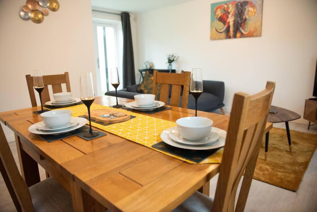 a wooden table with glasses of wine on top of it at Chi-Amici-3bed home-St Neots-Near to train station in Saint Neots