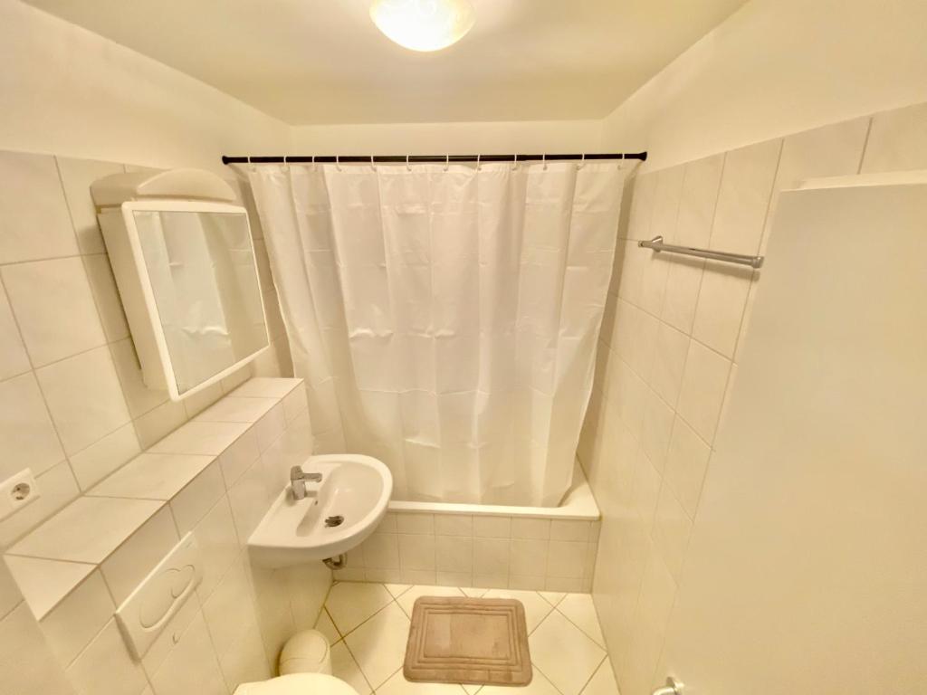 y baño blanco con lavabo y ducha. en Voll ausgestattete 3-Zimmer-Wohnung bei den Designer Outlets,VW, Autostadt & HBF, en Wolfsburg
