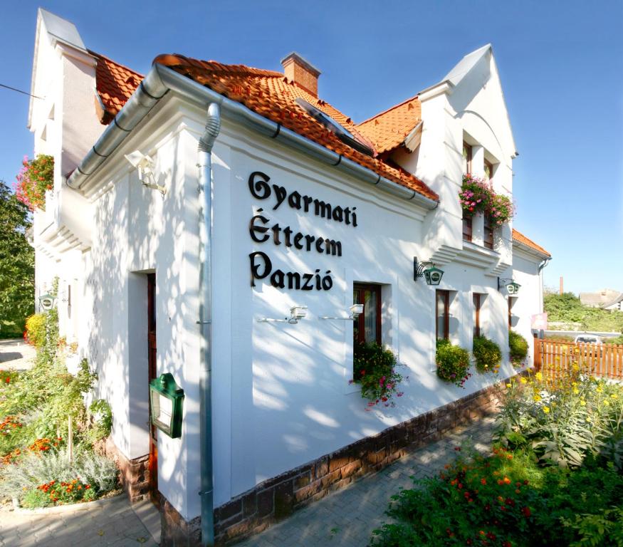 a white building with a sign on the side of it at Gyarmati Panzió & Étterem in Veszprém