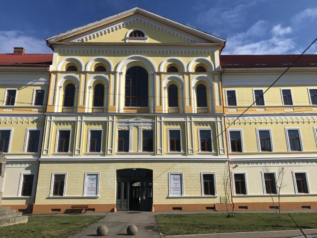 un grande edificio giallo con molte finestre di Palatul Lugoj a Lugoj