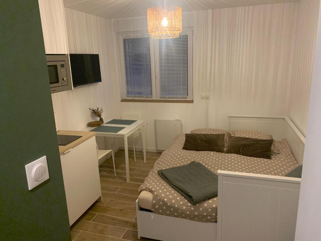 une petite chambre avec un lit et un bureau dans l'établissement Charmante studette au cœur du Plessis Robinson, au Plessis-Robinson