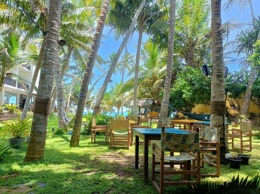 un patio con mesas y sillas bajo palmeras en Voulez-Vous, en Dikwella