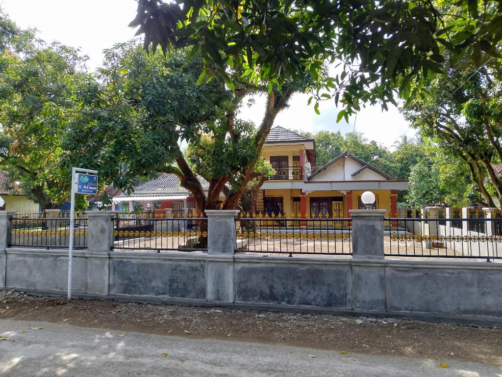 une clôture devant une maison avec un arbre dans l'établissement Homestay H mamun, à Cilowa