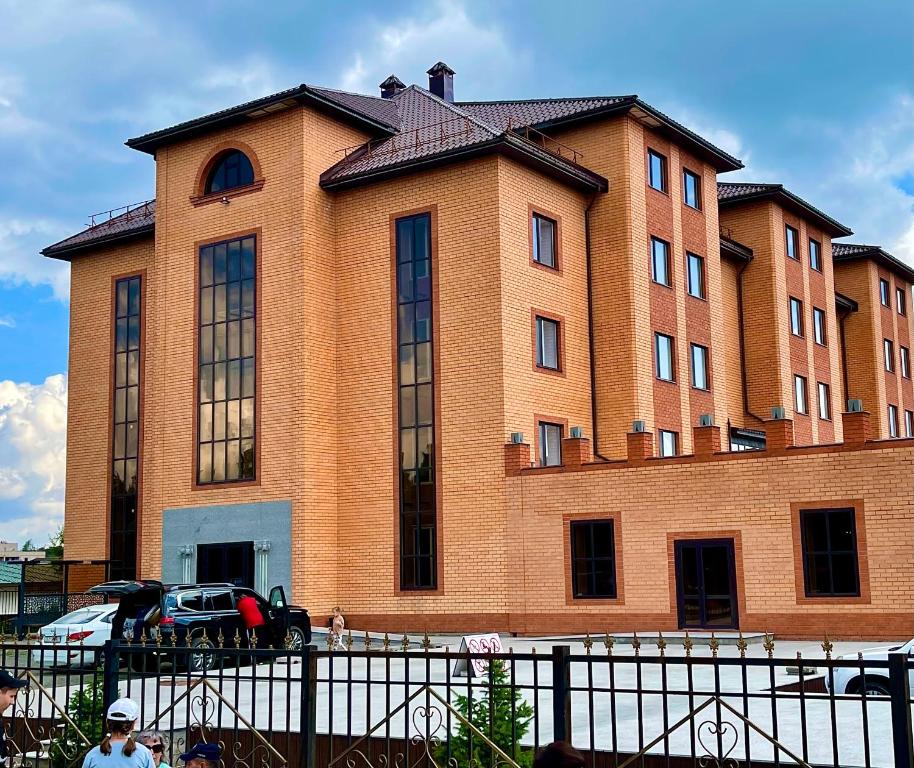 un gran edificio de ladrillo con un coche aparcado delante de él en Hotel Gloria Deluxe en Borovoye
