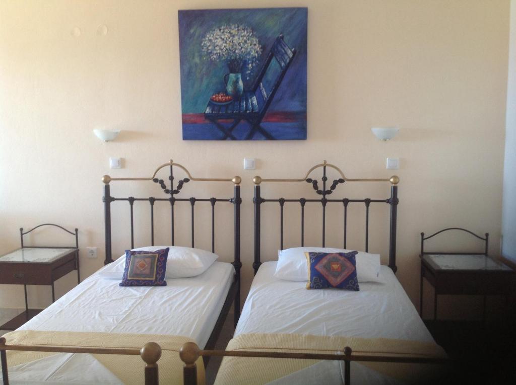 two beds in a room with a painting on the wall at Archipelagos Apartments in Arkasa