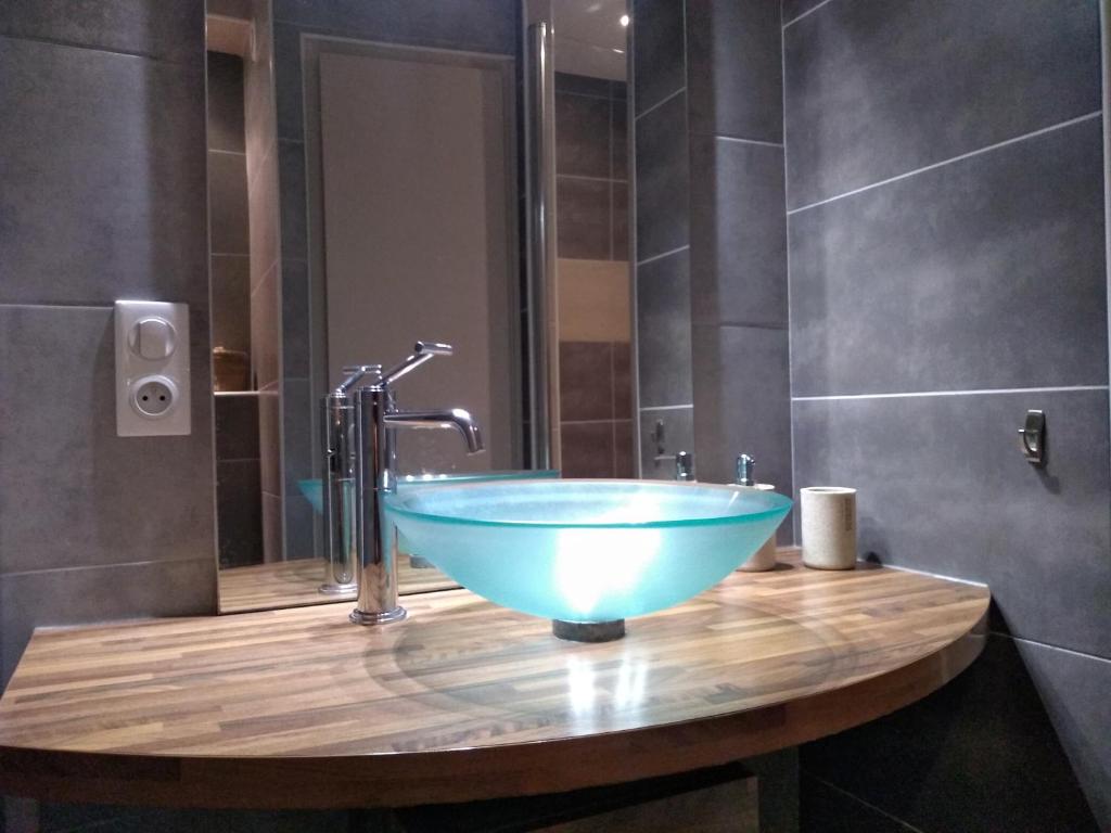 a bathroom with a blue bowl sink on a wooden counter at Passage du Cygne in Blois