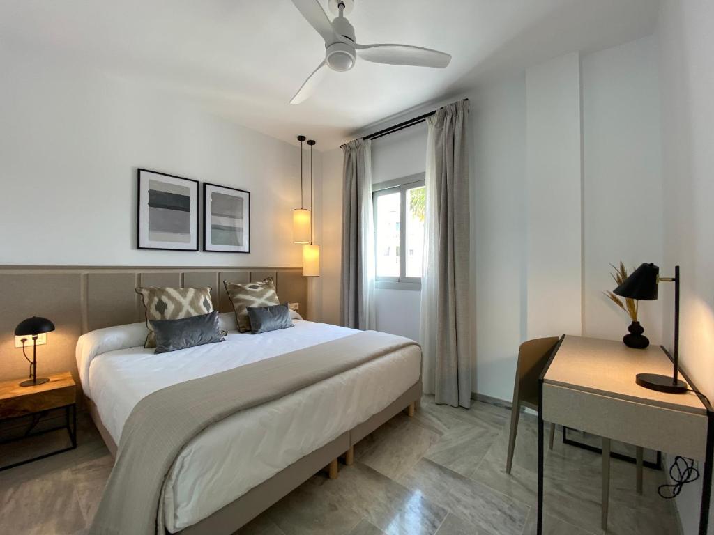 a white bedroom with a bed and a desk at Hotel Apartamentos Marina Luz in Chipiona