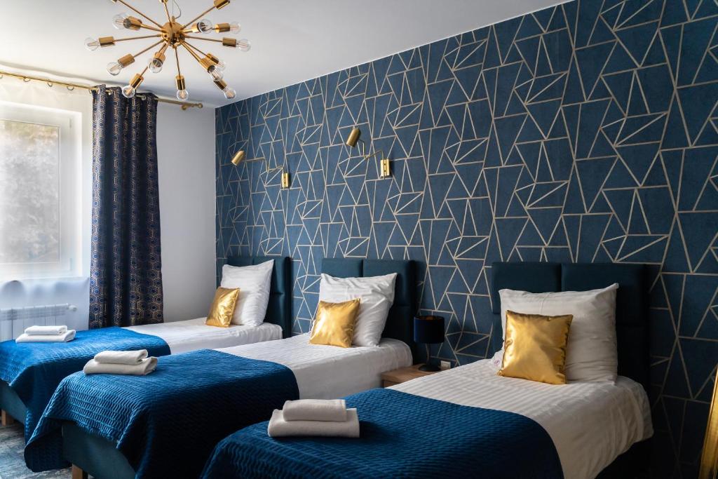 three beds in a room with blue and white at Pensjonat Wrzos in Poznań