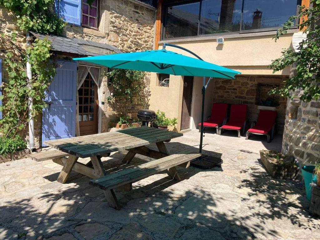 a picnic table with an umbrella and a grill at Gîte L'hirondelle in Meyrueis