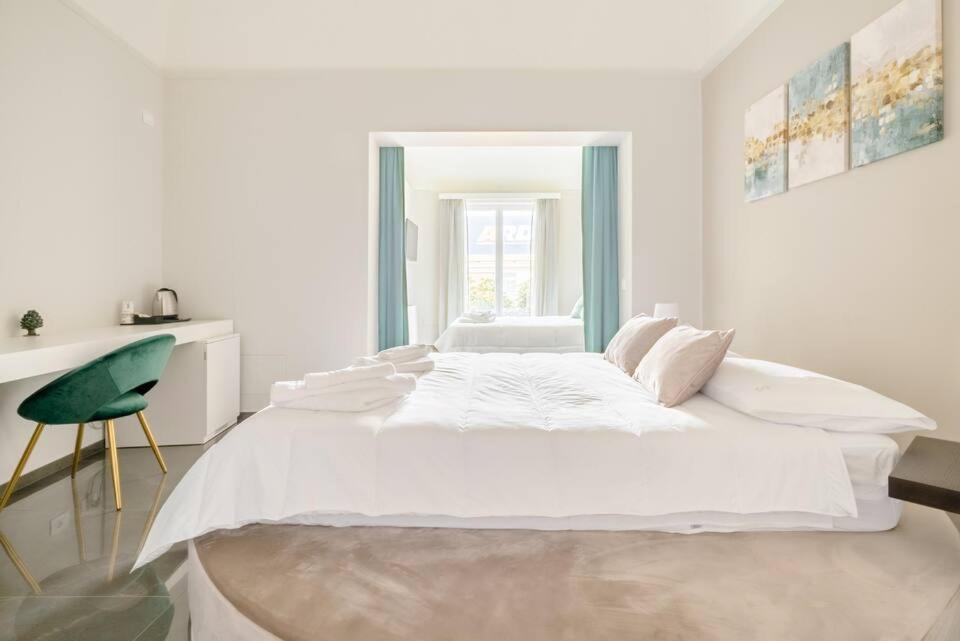 a white bedroom with a large bed and a green chair at Shoruq in Marsala