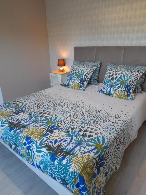 a bed with a blue and white comforter and pillows at chambre d'hôtes Les Hortensias in Saint-Jean-la-Poterie