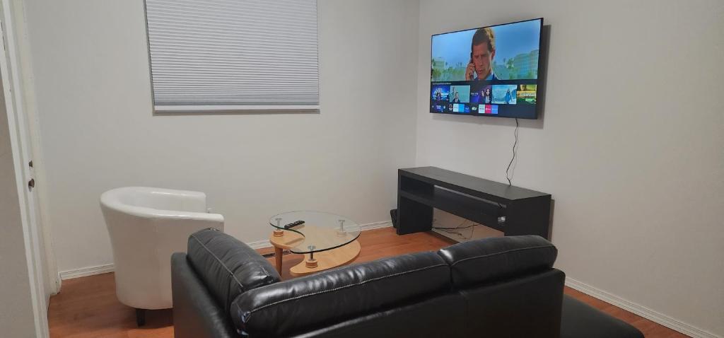 sala de estar con sofá de cuero y TV de pantalla plana en ChessKings Guest House - Unit 1, en Winnipeg