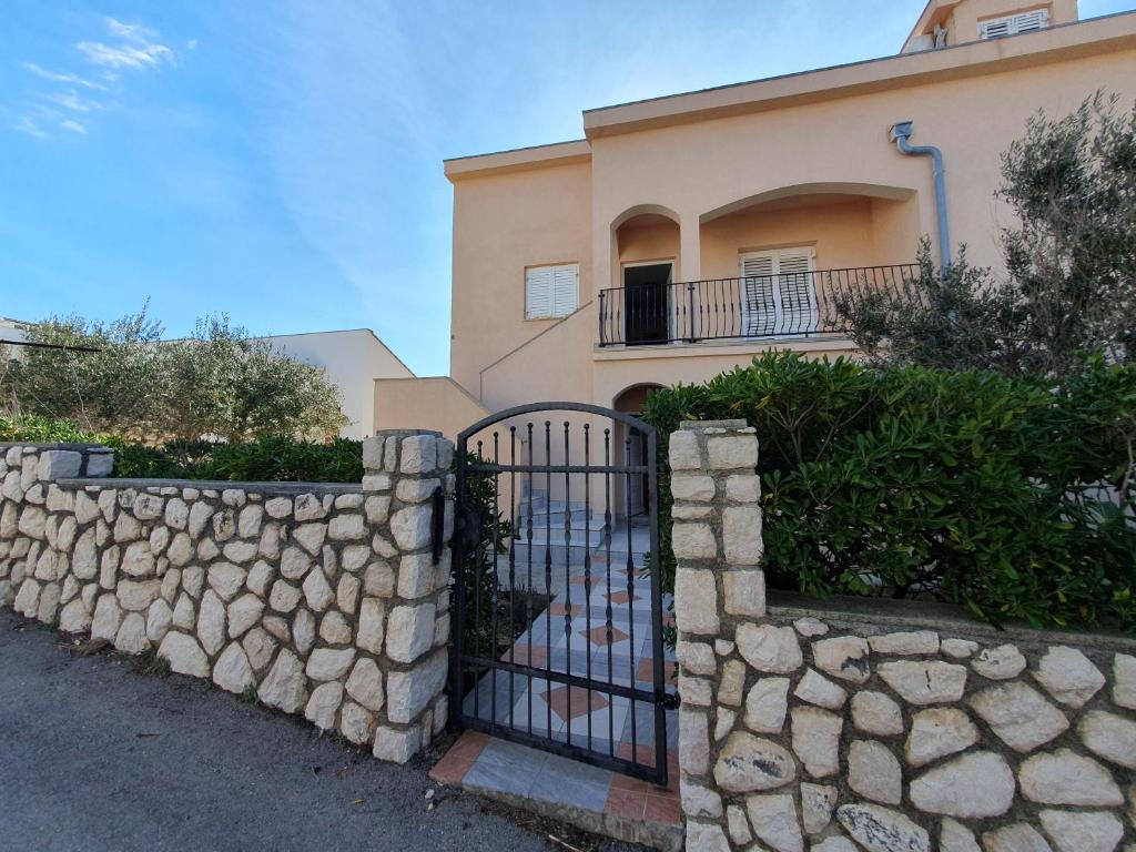 une clôture en pierre devant une maison dans l'établissement Olive garden Pag, à Pag