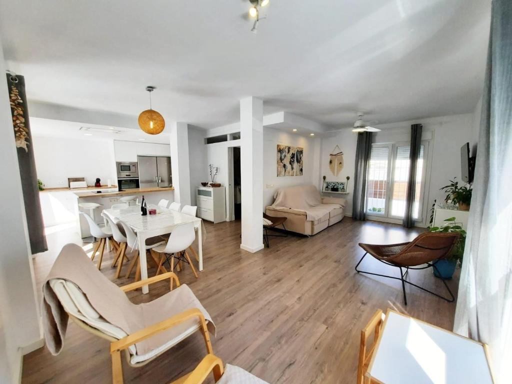 ein Wohnzimmer mit einem Tisch und Stühlen sowie eine Küche in der Unterkunft CASA DE DISEÑO EN LA PLAYA. in Rota