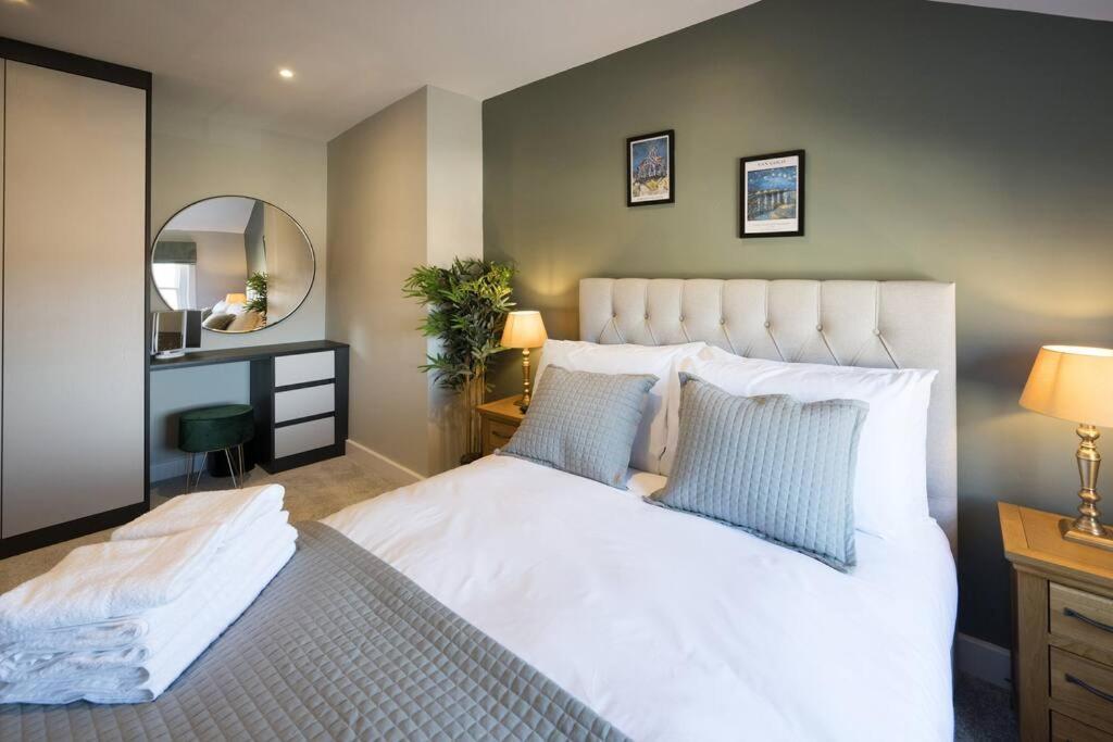 a bedroom with a large white bed and a mirror at Lettered Board Apartments 1, 2 & 3 in Pickering