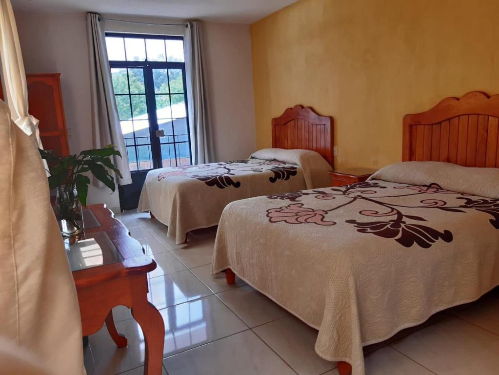 a hotel room with two beds and a window at HOTEL CAMELINAS AREA BLANCA in Pátzcuaro